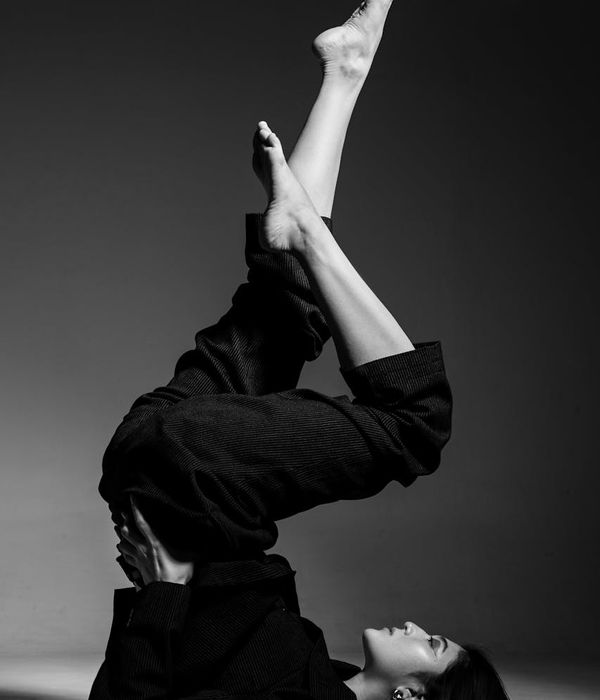 Woman in a graceful yoga pose against a dark, minimalist background.